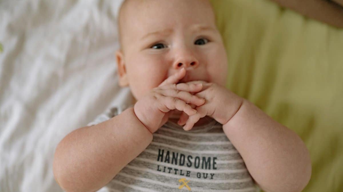 A close-up portrait of an adorable baby lying on a bed, showcasing innocence and curiosity.