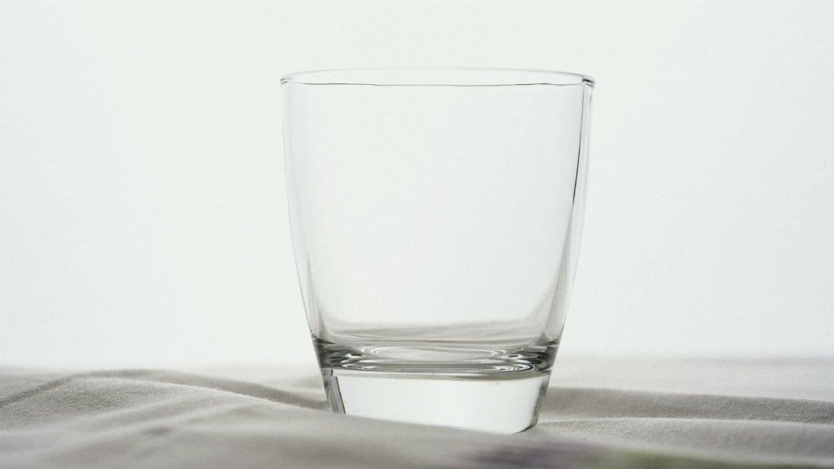 Elegant clear glass cup on a soft white surface offers versatile use for minimalistic settings.