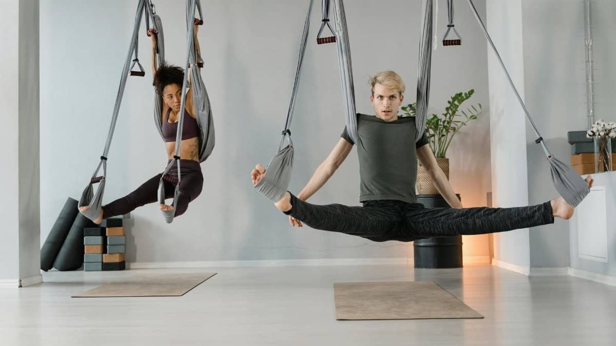 Two people practice aerial yoga in a modern studio, demonstrating flexibility and balance.
