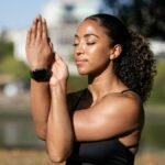 African American woman meditating outdoors, exuding relaxation and wellness.