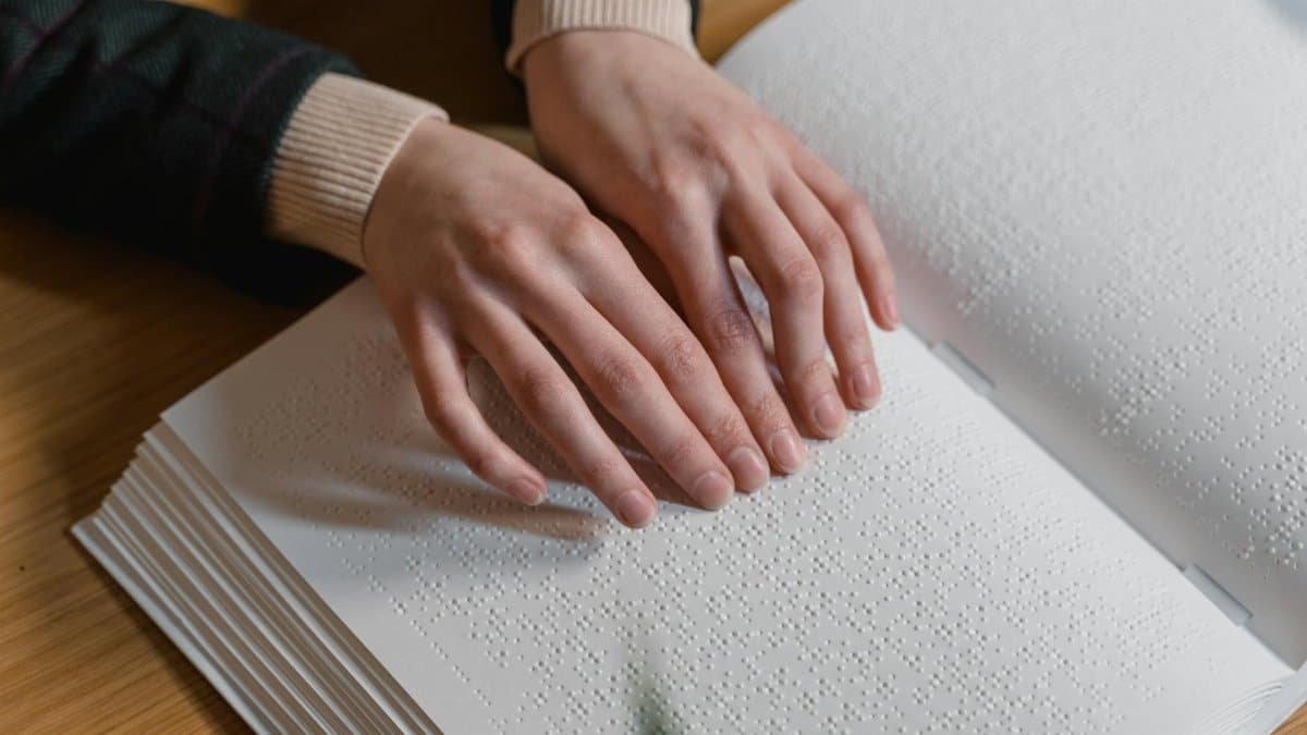 Close-up of hands reading Braille, symbolizing independence and accessibility for the visually impaired.