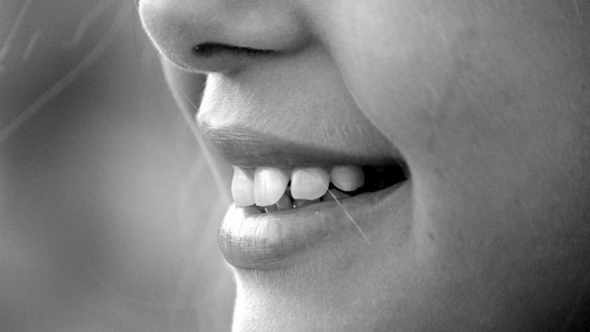 A monochrome close-up of a smiling face showcasing teeth and lips.