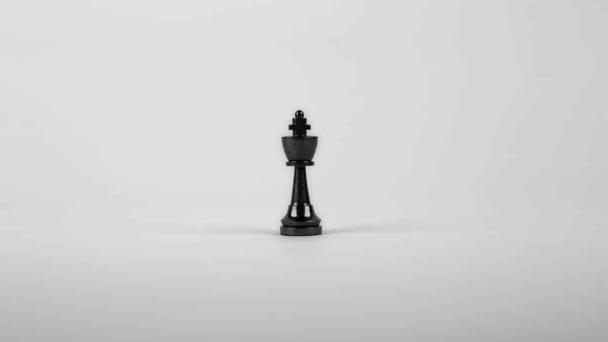 A minimalist black chess king piece on a white background, representing strategy and power.