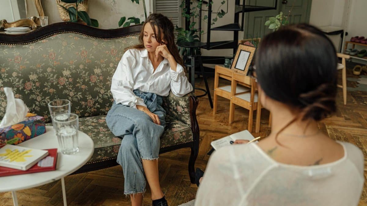 A thoughtful counseling session between a psychologist and a patient in a cozy, well-decorated room.