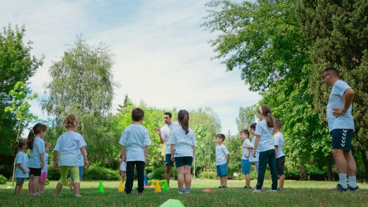 Group of kids learning and playing with teachers in a sunny park.
