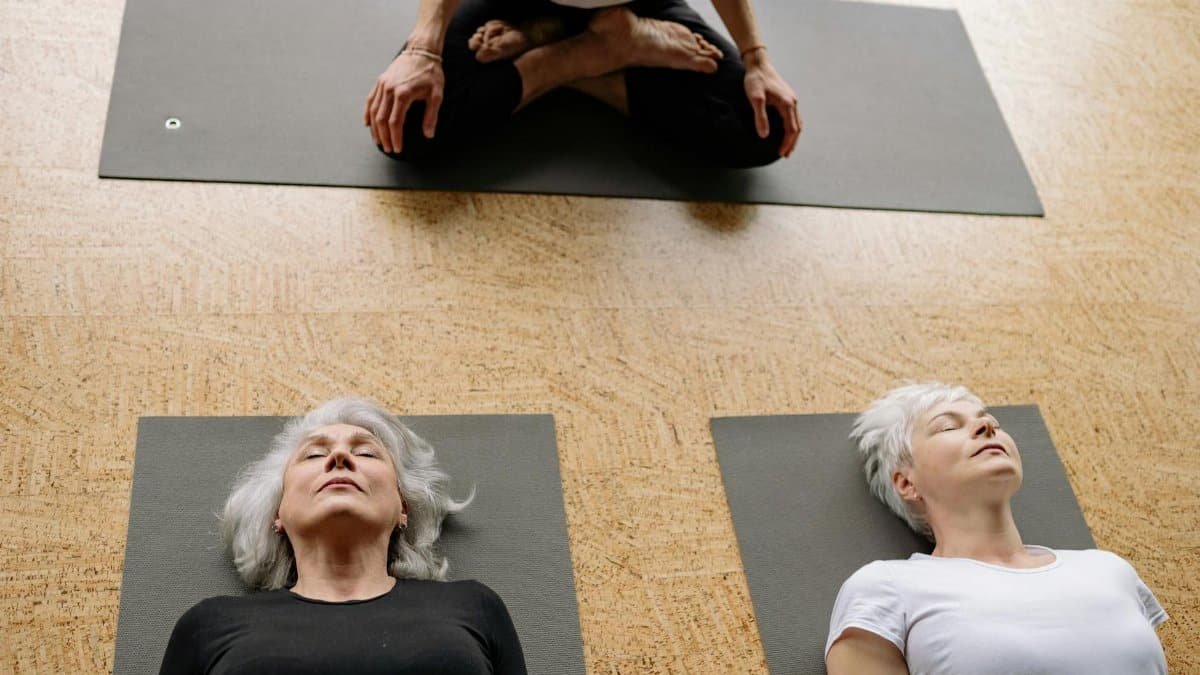 Two senior women practicing yoga in a studio setting for relaxation and well-being.
