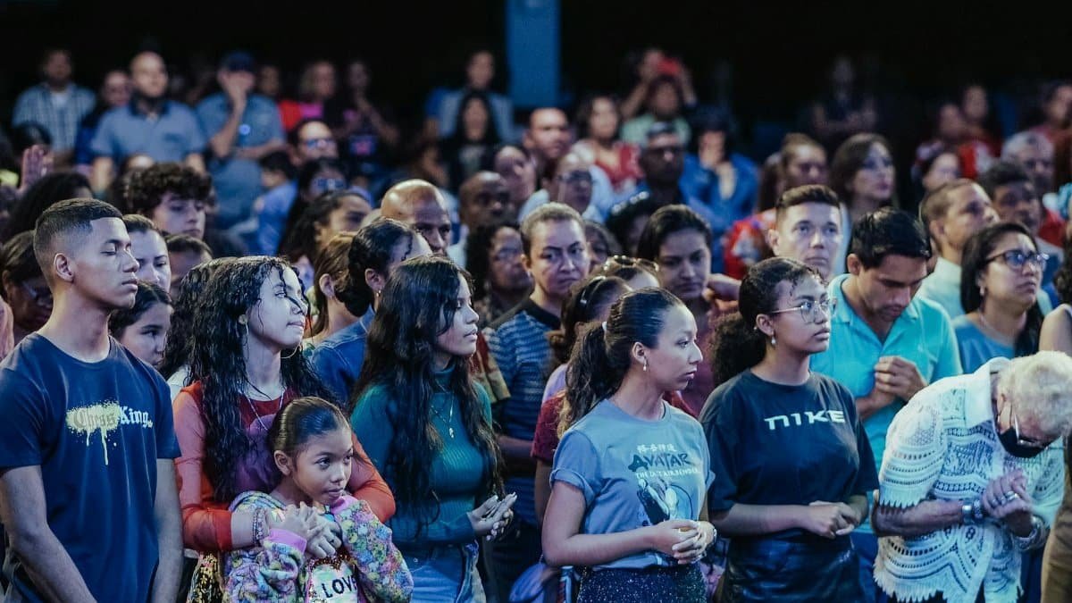 A diverse crowd attentively listening at an indoor gathering.