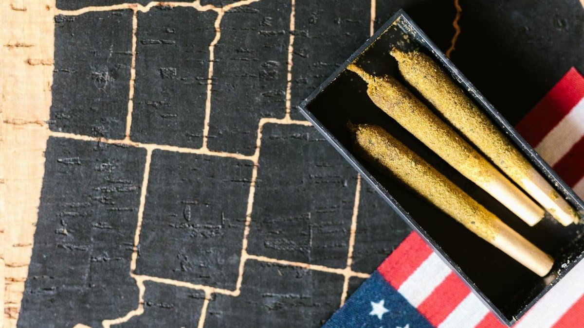 Close-up of cannabis joints on a rustic map with an American flag. Ideal for discussing marijuana culture.