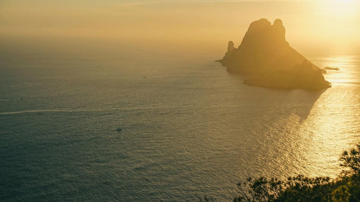 Sunset casting golden hues over ocean with tranquil silhouette of islands. Peaceful and captivating.