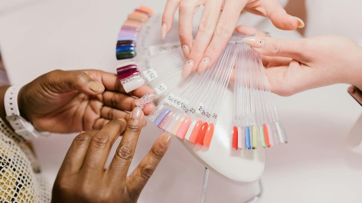 Close-up of hands choosing from a vibrant nail polish sample palette in a salon setting.