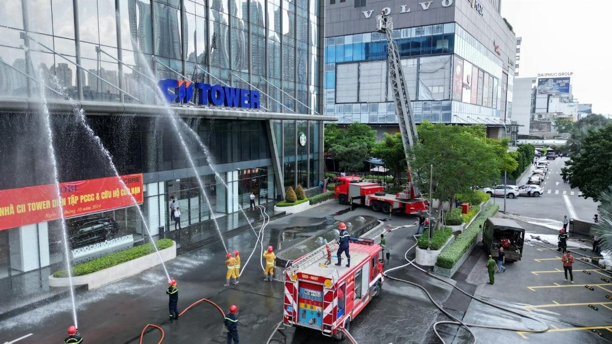 Firefighters conducting a drill with trucks and hoses at a high-rise office building.