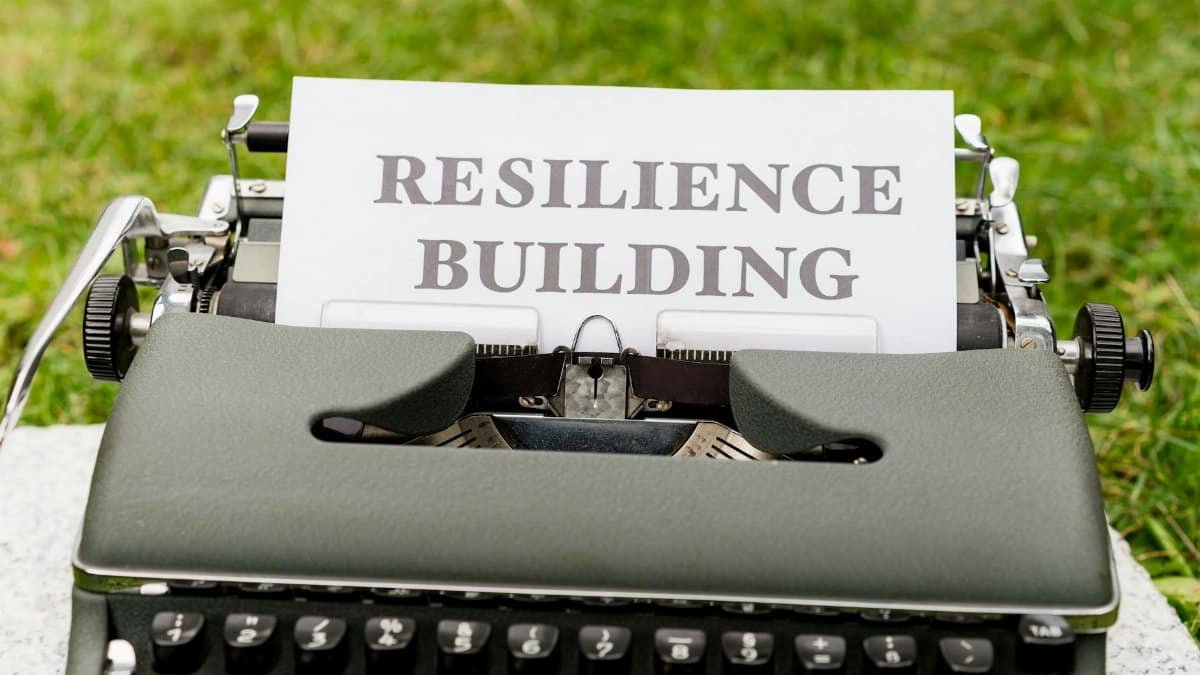 Vintage typewriter with 'Resilience Building' text on paper, set outdoors on grass.
