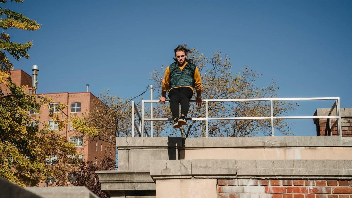 Full body of concentrated male athlete performing stunt on brick building while training outdoors