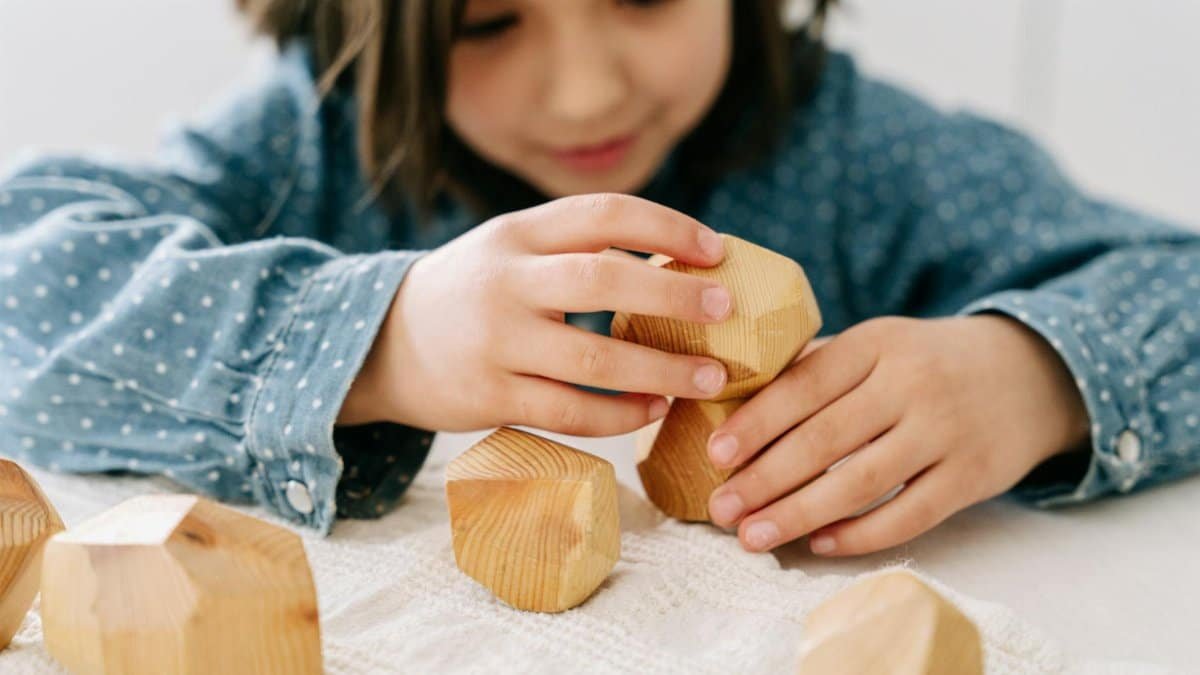 A young girl stacking wooden blocks, engaging in mindful play for cognitive development.