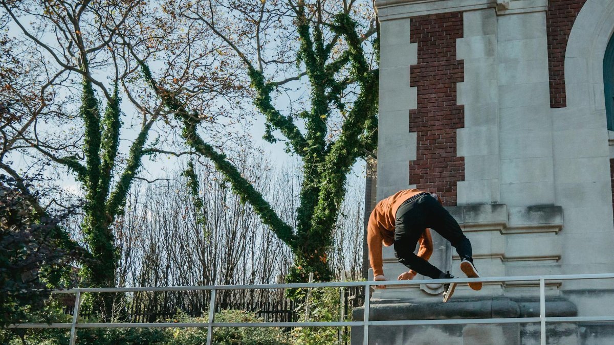 A skilled athlete in action, performing parkour on urban infrastructure, showcasing agility and strength.