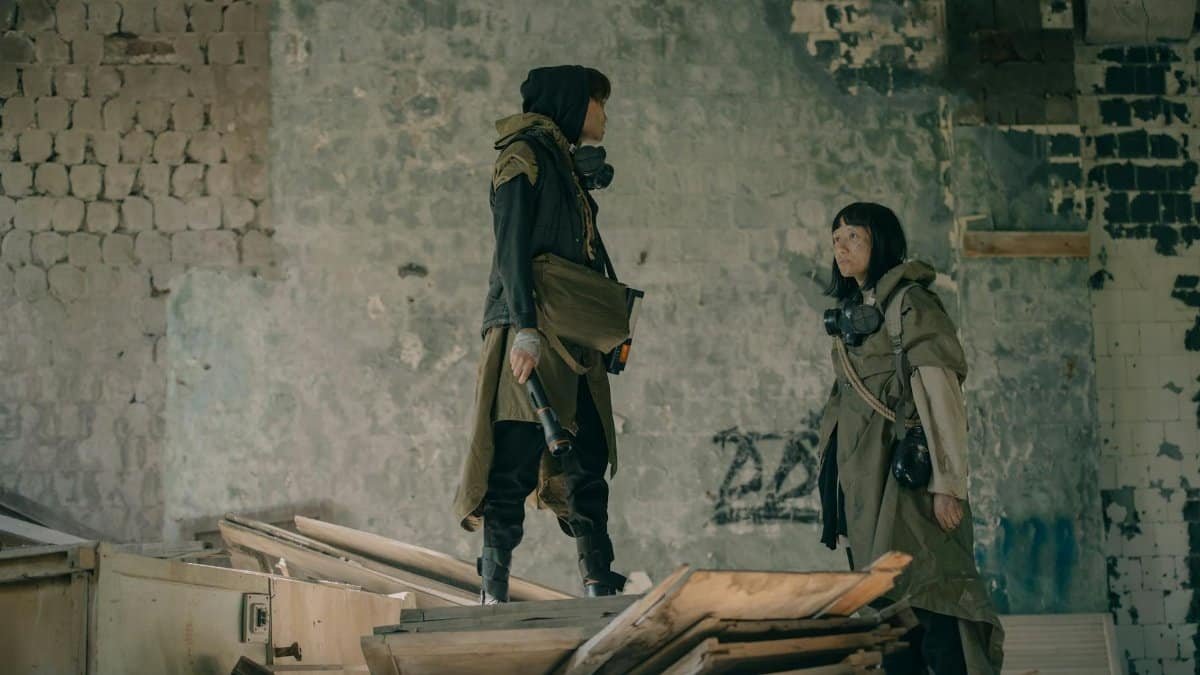 Two people in urban survival gear explore a dystopian, abandoned building setting.