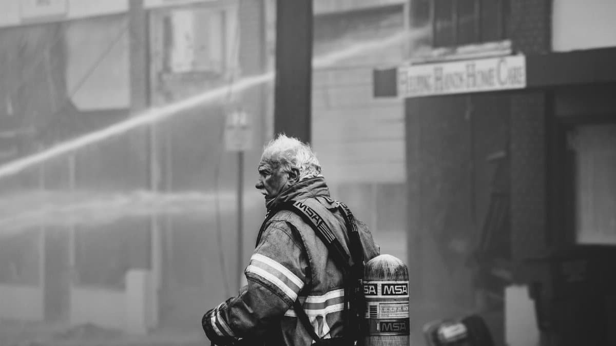 Heroic firefighter in protective gear managing a city fire, showcasing bravery and resilience.