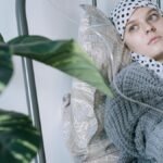 Young woman in hospital bed receiving cancer treatment, reflecting resilience.