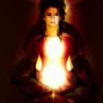 A woman in meditation surrounded by a radiant aura, symbolizing spiritual energy and enlightenment.