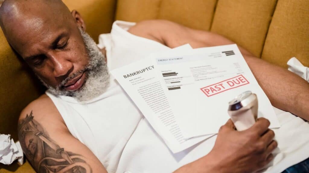 Sleeping man with financial documents, symbolizing stress and bankruptcy.