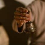 A person holding a Tibetan bell, symbolizing healing and meditation practices.