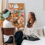 Two women sharing a mindful and spiritual moment in a cozy, indoor setting, promoting wellness and connection.