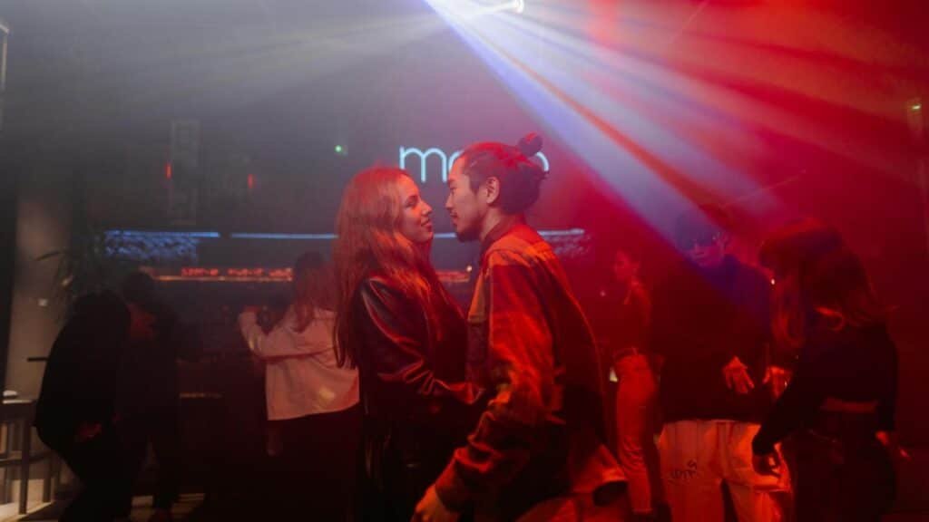 Energetic nightclub scene with couples dancing under vibrant lights.