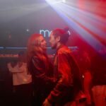 Energetic nightclub scene with couples dancing under vibrant lights.