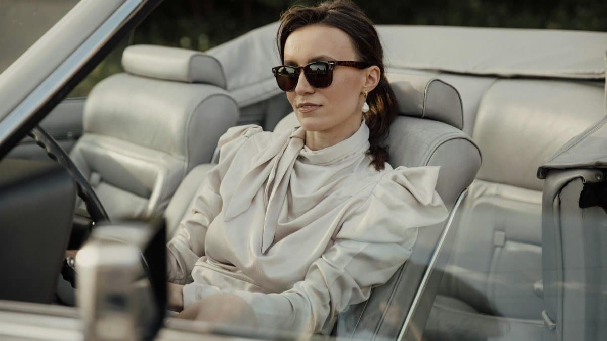 Stylish woman in sunglasses driving a classic convertible car, exuding elegance and class.
