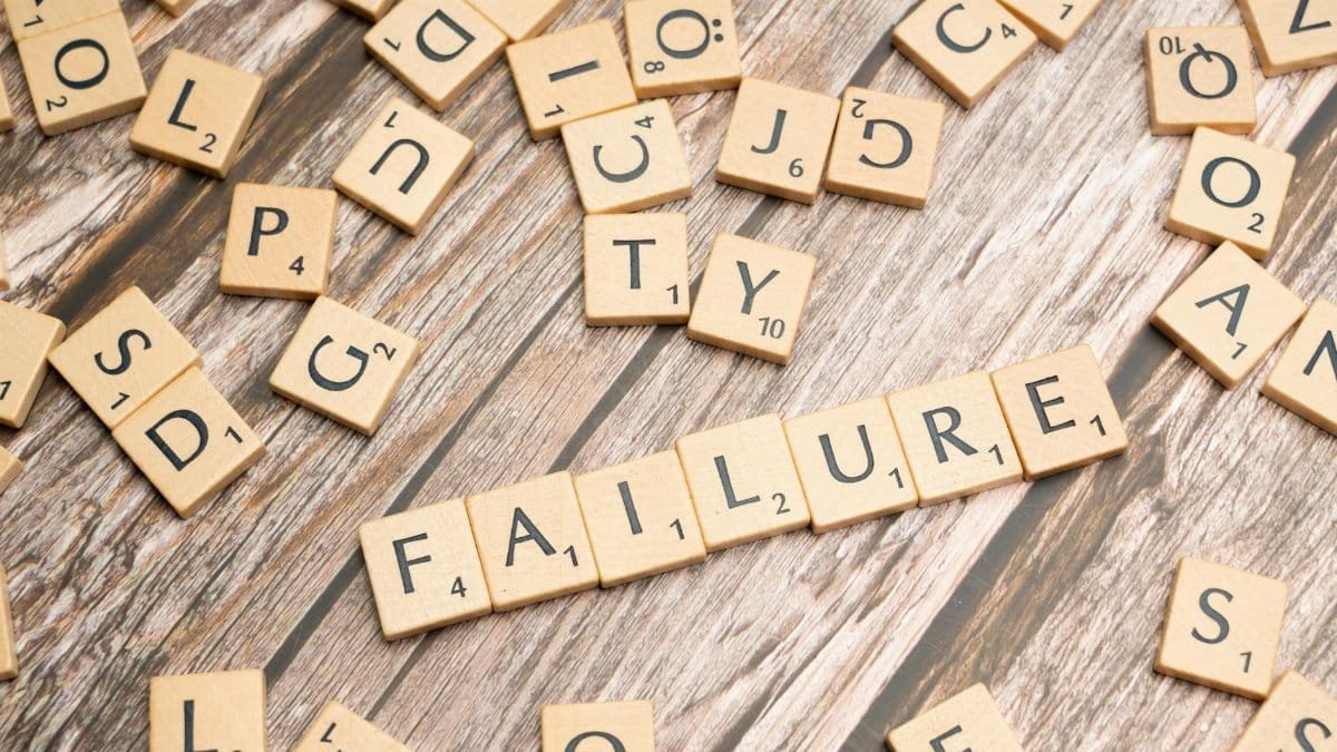 Wooden letter tiles spelling 'failure' on a wooden table, representing challenges.