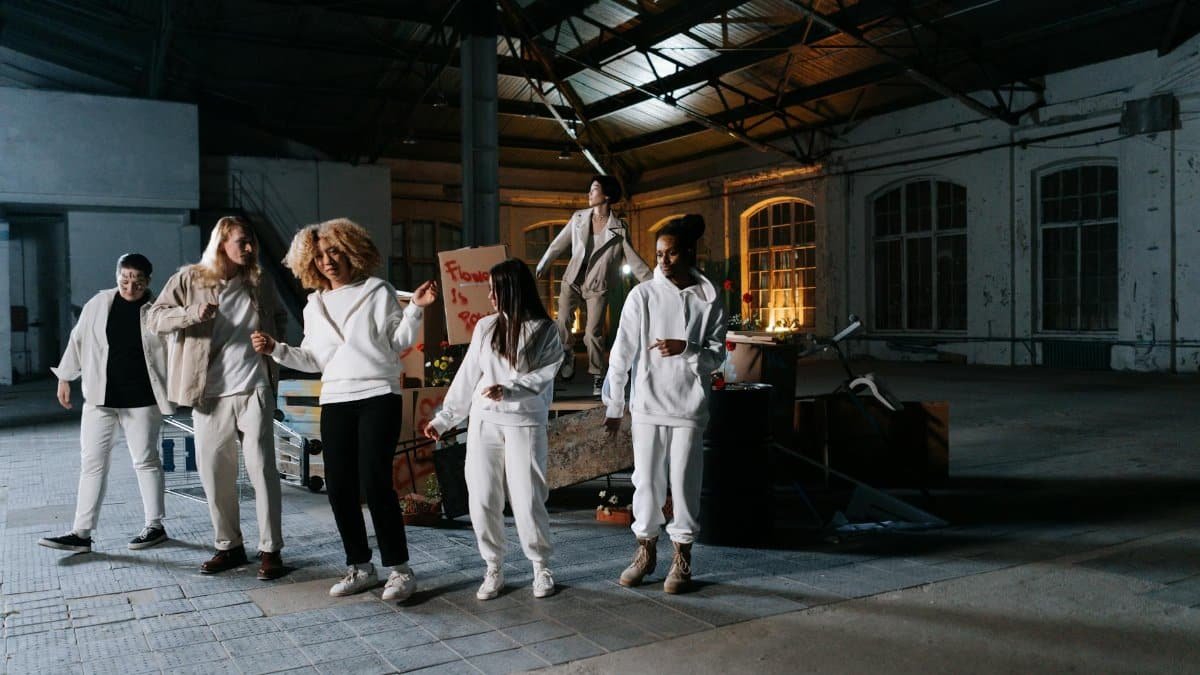 A group of diverse individuals performing a modern dance in an urban industrial setting.