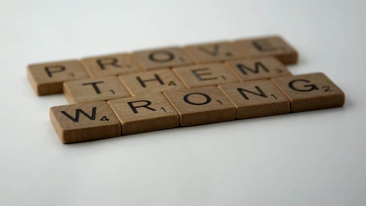 Scrabble tiles spelling 'Prove Them Wrong' on a white background, conveying motivation.