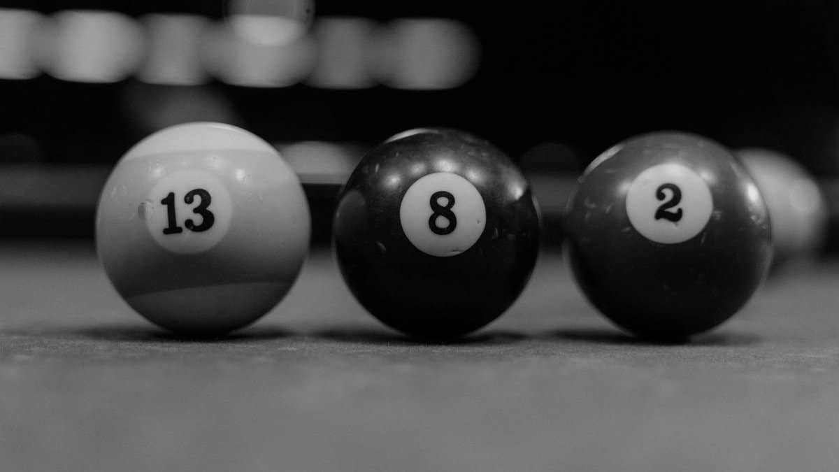 A black-and-white close-up shot of billiard balls 13, 8, and 2 on a pool table, showcasing depth of field.