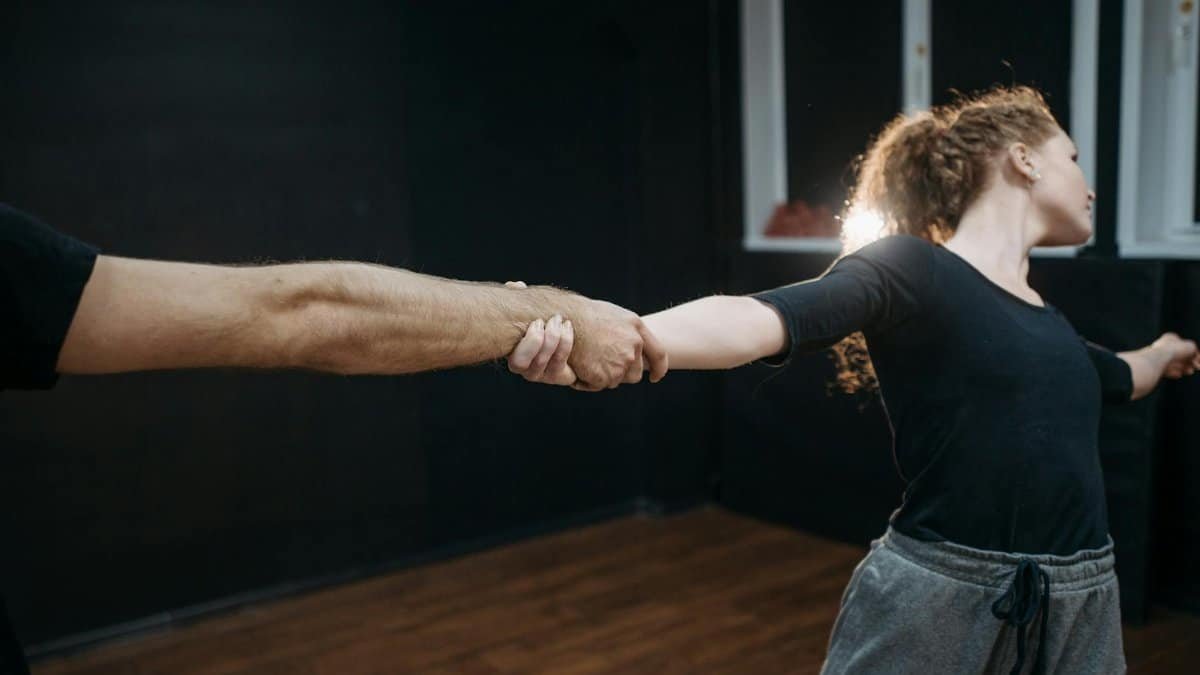 A young couple practicing dance moves indoors, focusing on coordination and precision.