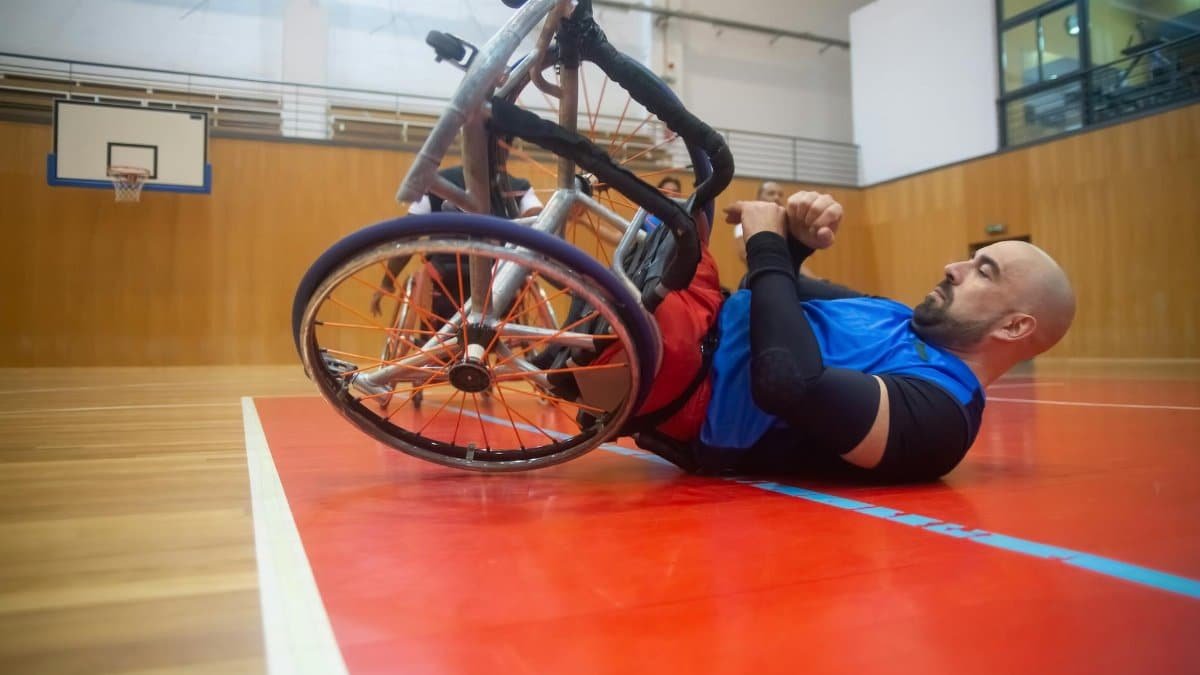 An athlete in a wheelchair practices basketball indoors, showcasing determination.