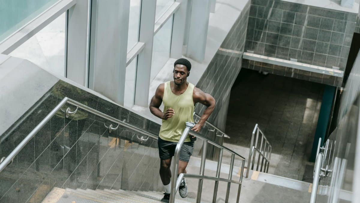 Muscular man in activewear running upstairs inside a modern building. Fitness concept.
