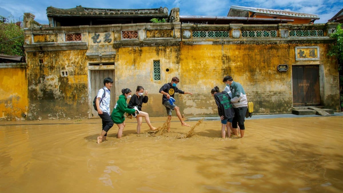 Six young individuals walk through a flooded street in Hoi An, showing resilience and togetherness.