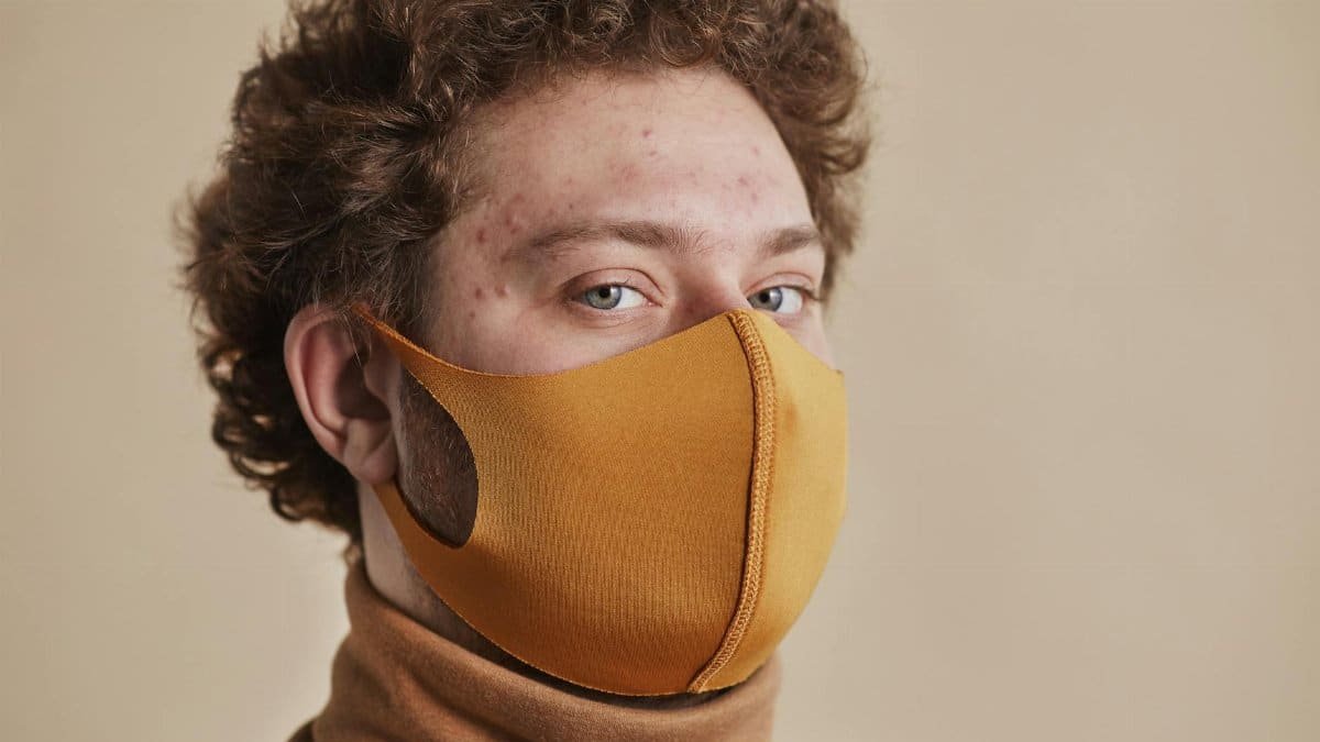 Portrait of a young adult wearing a fashionable orange face mask, symbolizing the new normal.