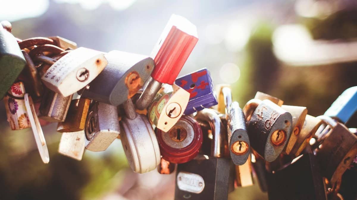 Variety of colorful padlocks clinging to a wire, symbolizing love and commitment.