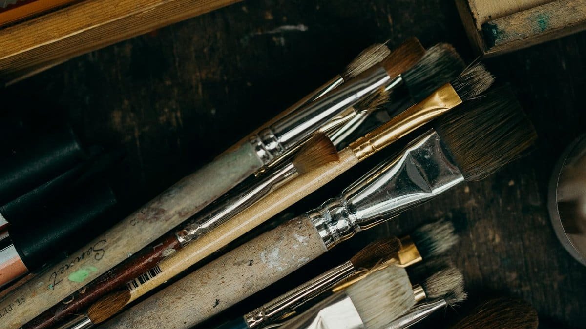 Close-up of various used paintbrushes in an artist's studio setting.