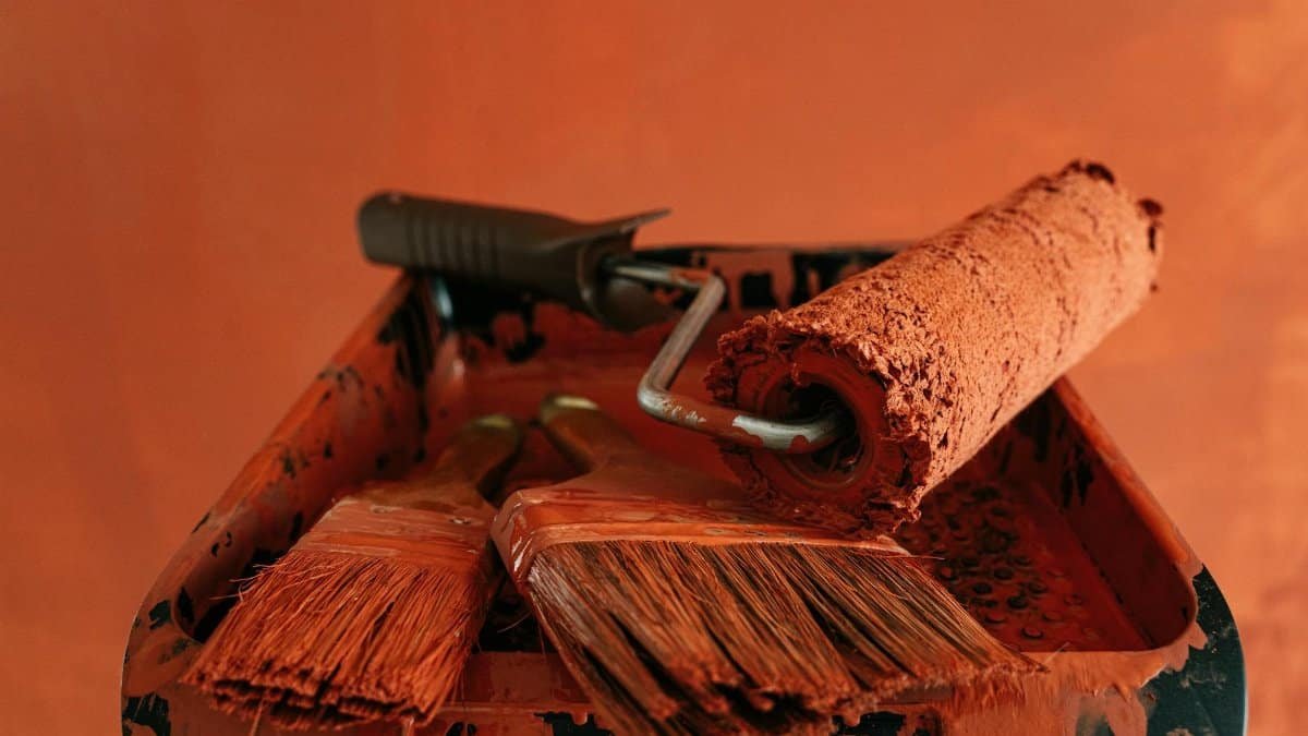 Orange paint tools in a messy tray, perfect for renovation themes.
