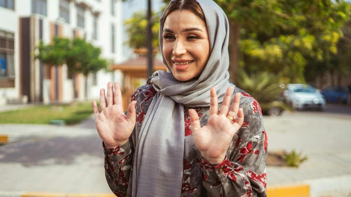 A joyful middle-aged woman in a hijab smiles outdoors in Baghdad, showcasing cultural diversity.