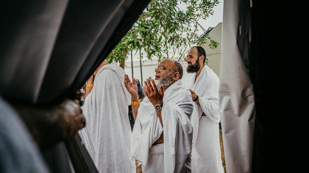 A group of men in white robes participate in a spiritual prayer outdoors, embracing cultural and religious traditions.