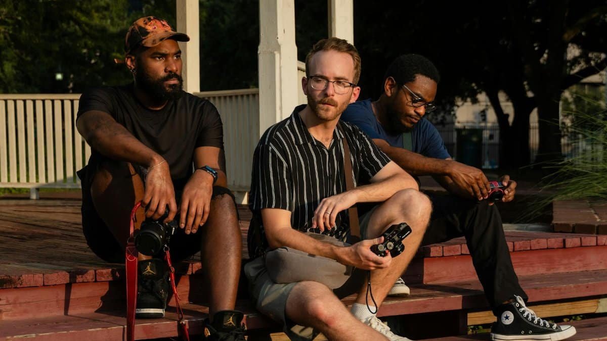 Three friends sitting on steps with cameras on a sunny day in Houston.