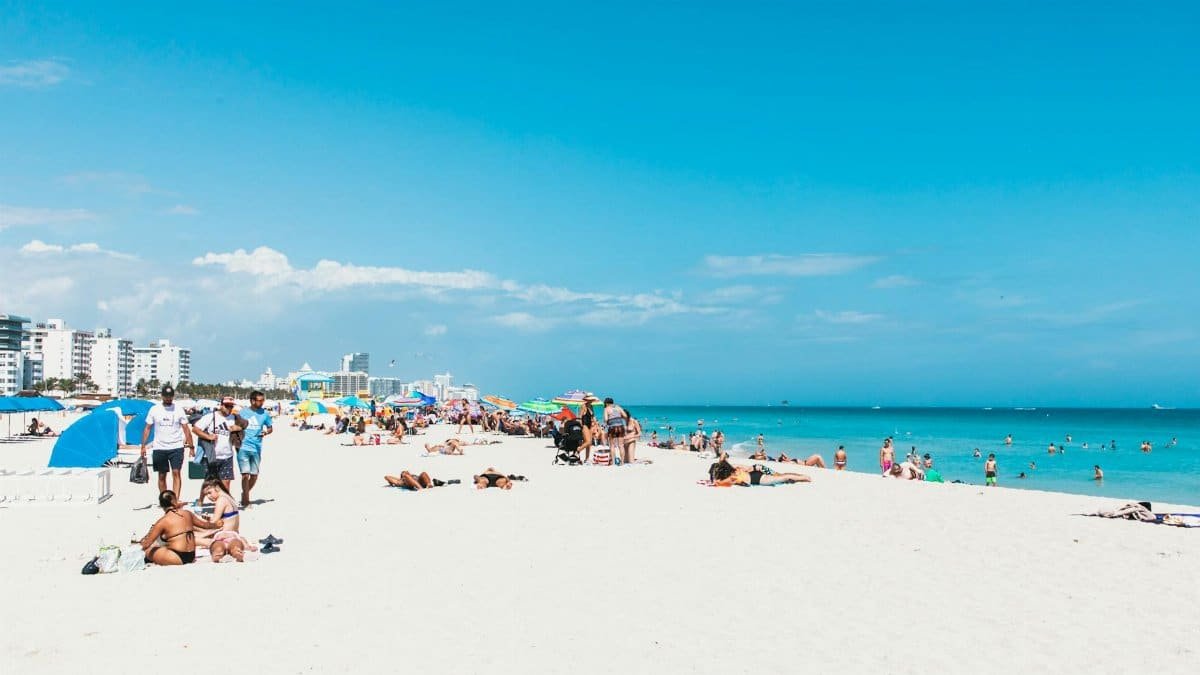 A lively summer day at Miami Beach with sunbathers and colorful umbrellas.
