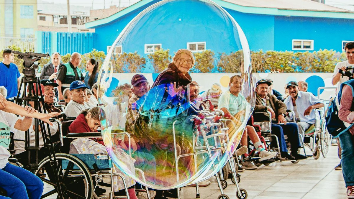 Elderly people enjoying a fun moment with a giant bubble outdoors in Lima, Peru.