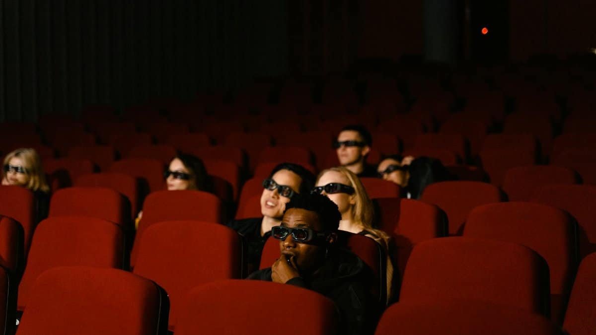 A diverse group of people wearing 3D glasses watching a movie in a theater.