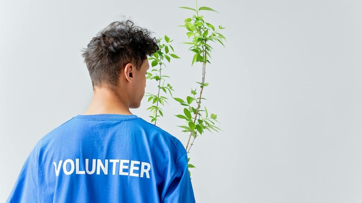 Young volunteer in blue shirt nurturing plant, symbolizing eco-friendly initiatives.