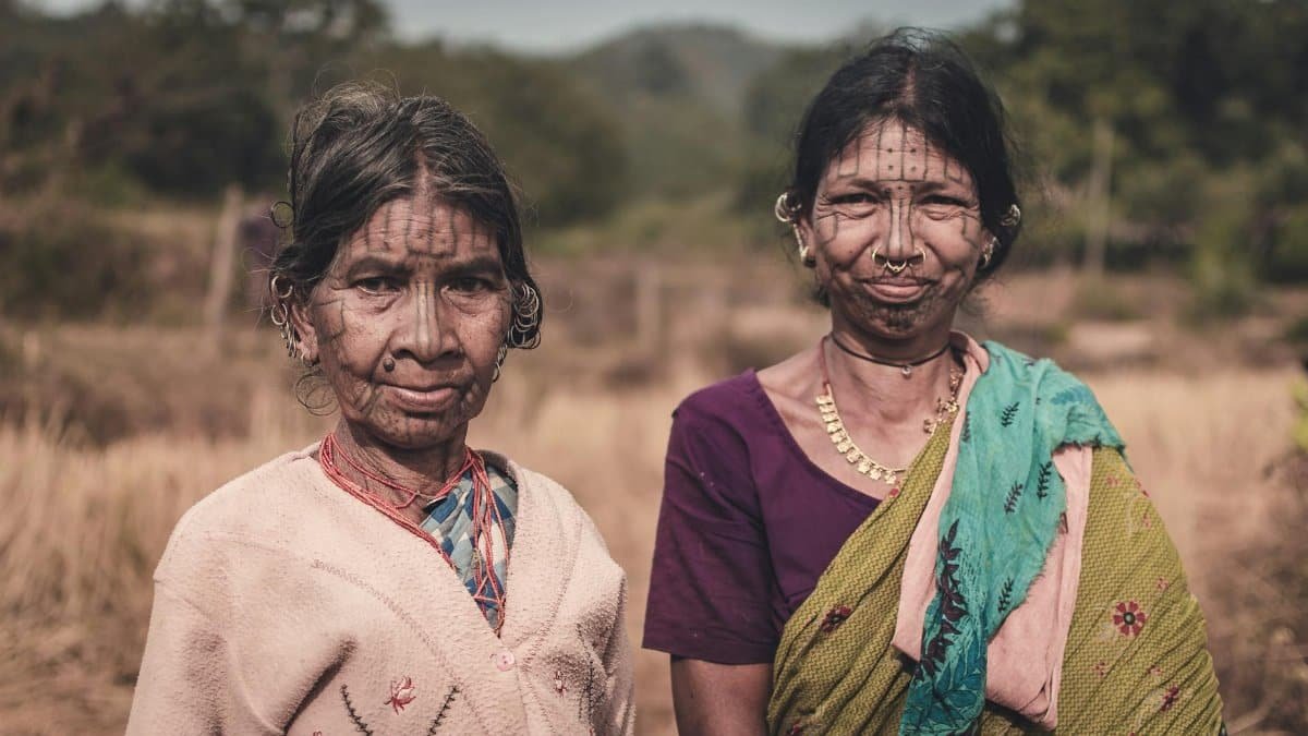 Portrait of two tribal women in Odisha, India, showcasing traditional jewelry and facial tattoos.