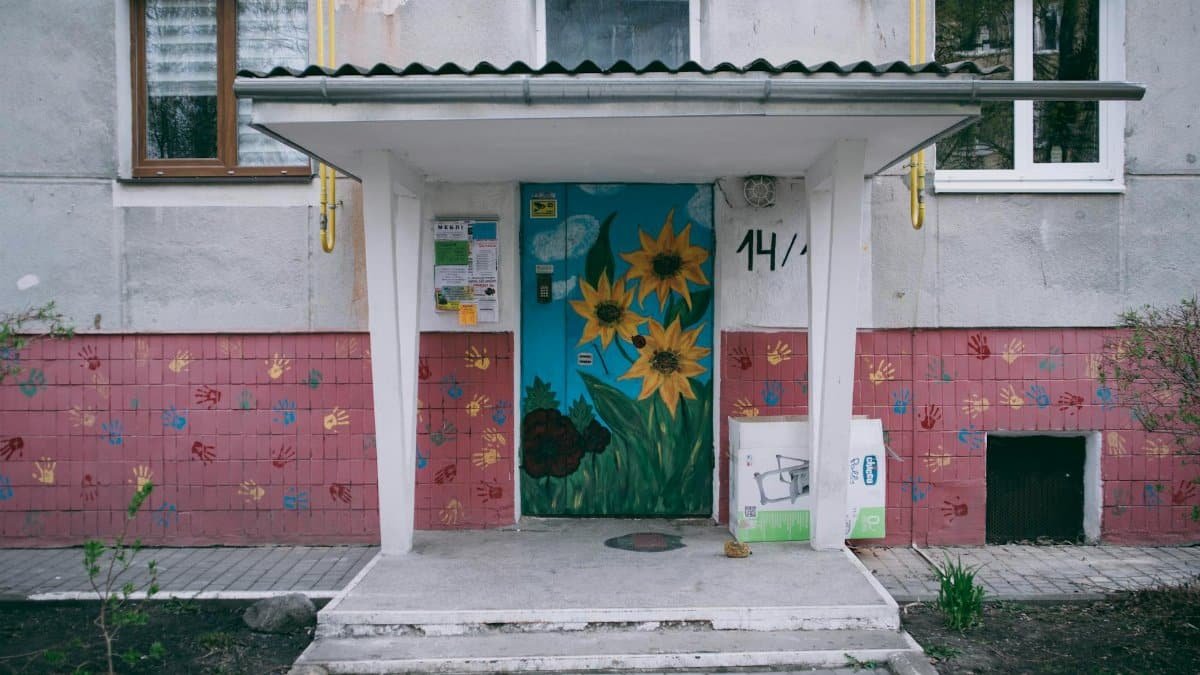 Vibrant art and flower murals adorn a city's apartment building facade.